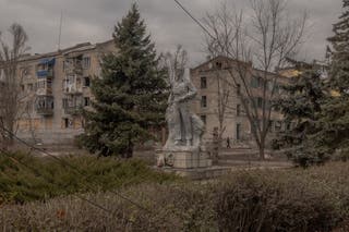 A person walks past residential buildings heavily damaged by shelling in Lyman, Donetsk region, on 1 February 2025